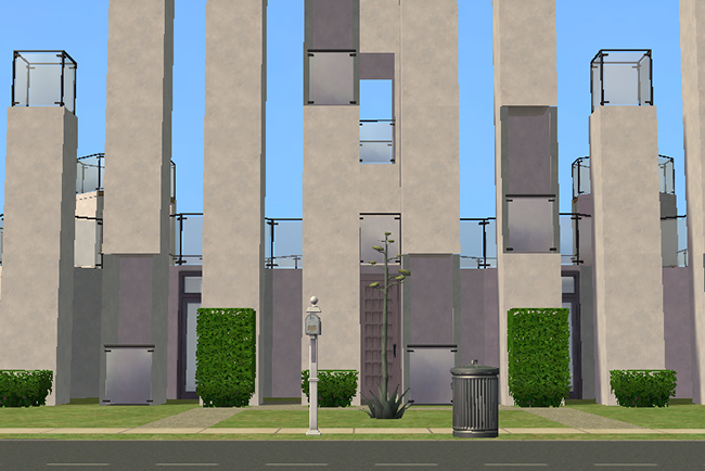 Front entrance view of Blue Harvest showing massive vertical tower columns surrounding a recessed modern entryway with trimmed hedges and stark minimalist landscaping.