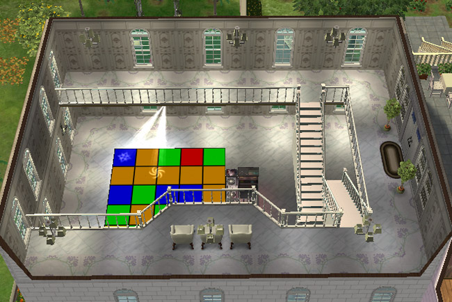 A bright ballroom has a colorful dance floor, pale walls, stair railings, tall windows, balcony seating, and open space for dancing.