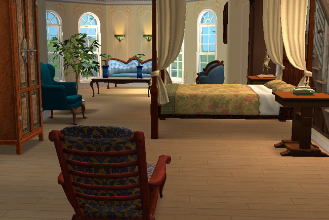 A hotel suite has warm gold walls, a double bed, draped curtains, arched windows, a sitting area, a writing desk, and colorful chairs.