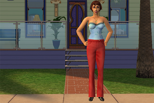 Portrait of Lorraine Keller standing outside her colorful suburban home featuring palm trees, decorative windows, dark rooflines, and warm Indian-inspired design accents.