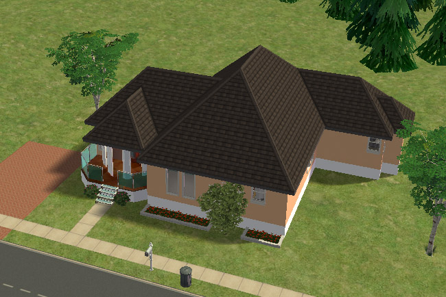 An angled exterior view of a tan one-story home with a dark roof, glass front porch, flower beds, shrubs, and driveway space beside the house.