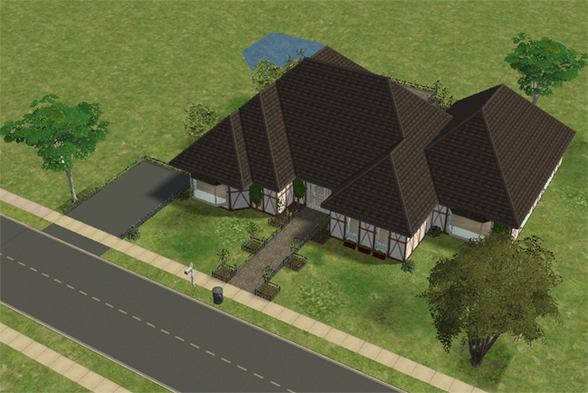 An angled exterior view of the home with layered rooflines, a driveway, front landscaping, Tudor-style trim, and water visible behind the lot.