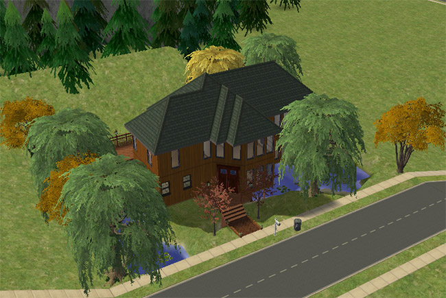 An angled view shows the house surrounded by trees and water, with a wraparound deck and dark green roof.